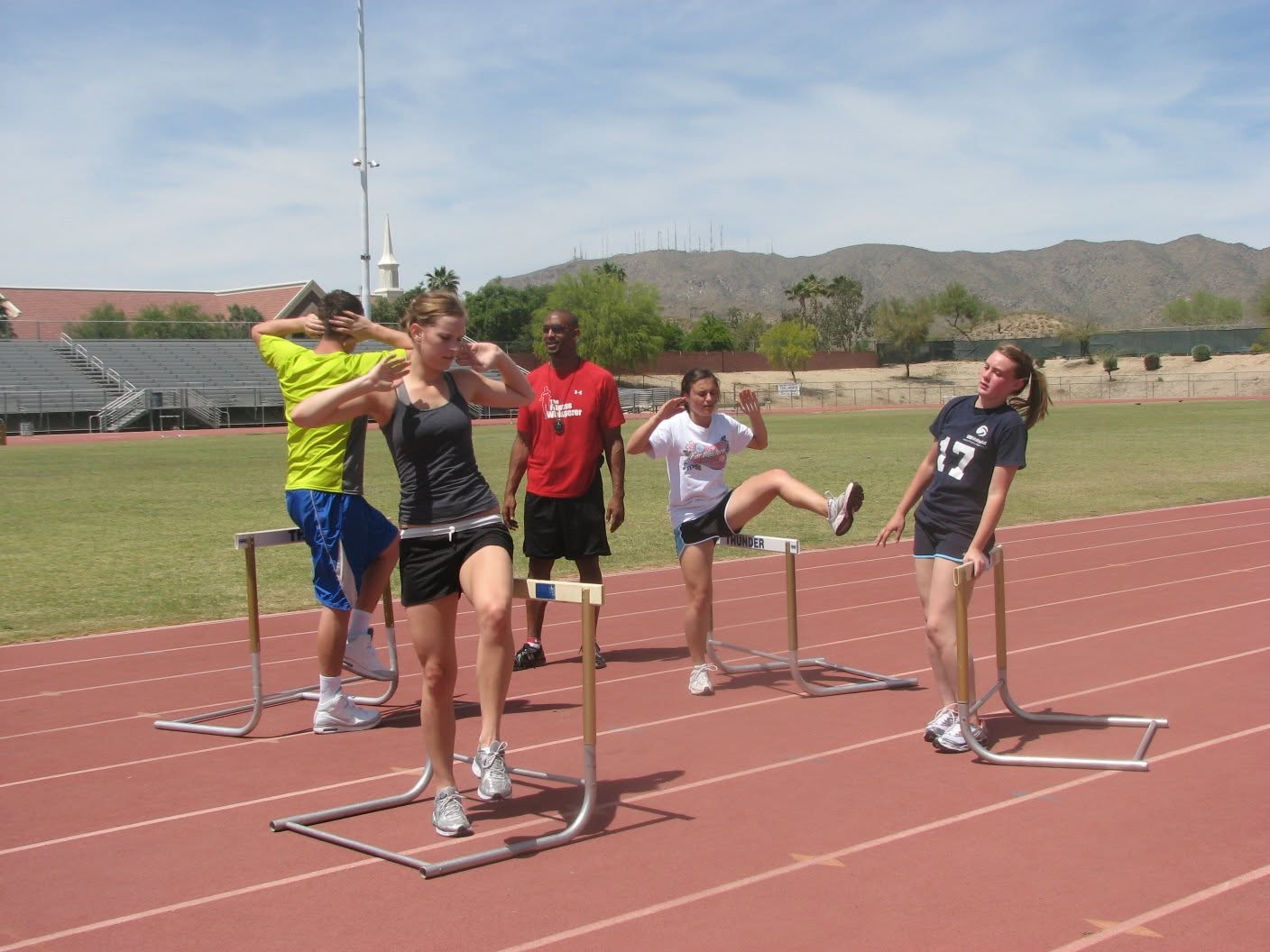 Outdoor hurdle drills with Larry coaching the group.